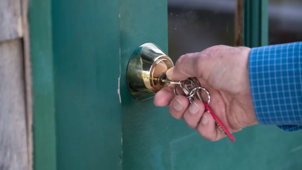 Hand opening a door lock by turning a key
