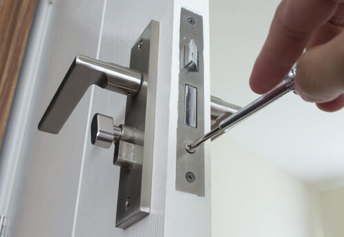 Locksmith installing a lock on a white door